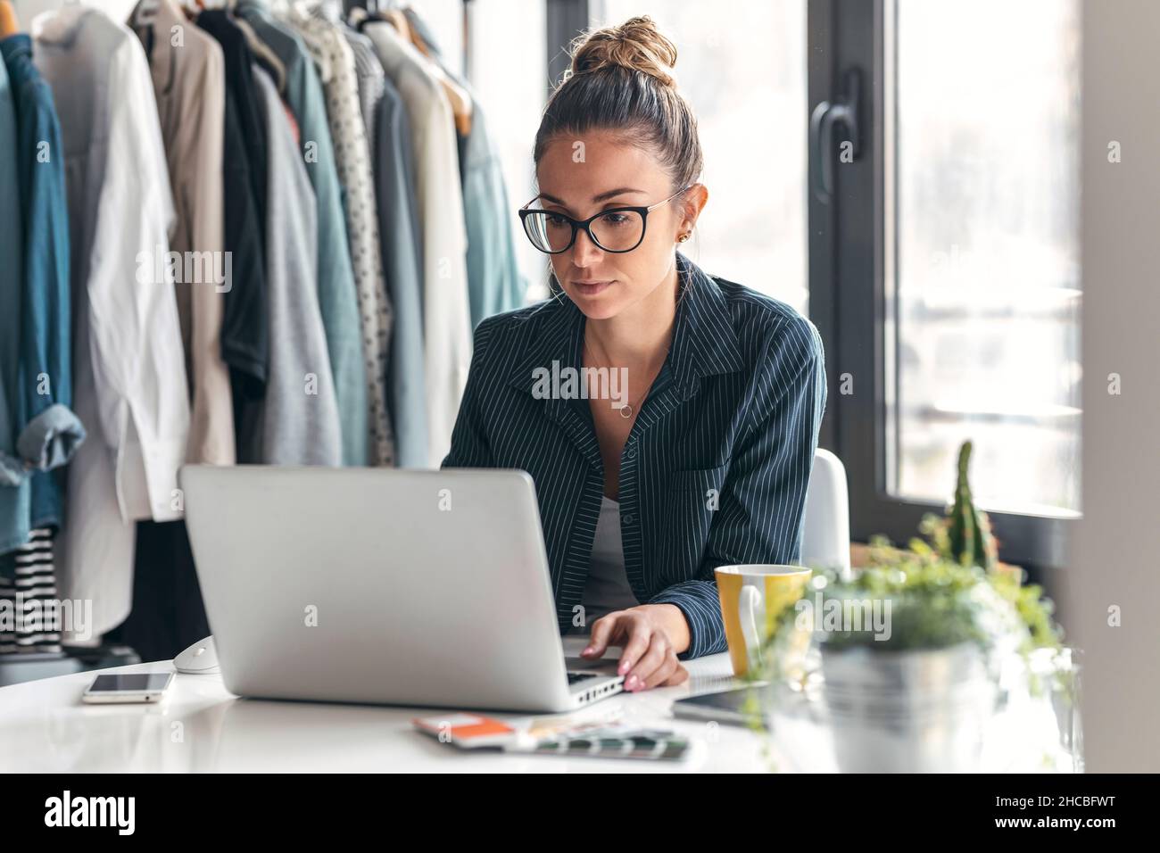 Giovane stilista che usa un computer portatile alla scrivania Foto Stock