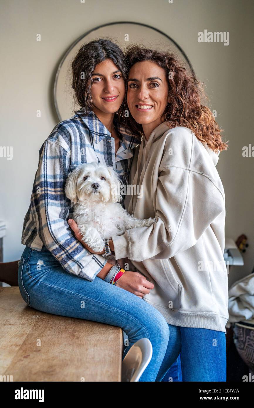 Felice madre con figlia seduta con cane a tavola Foto Stock