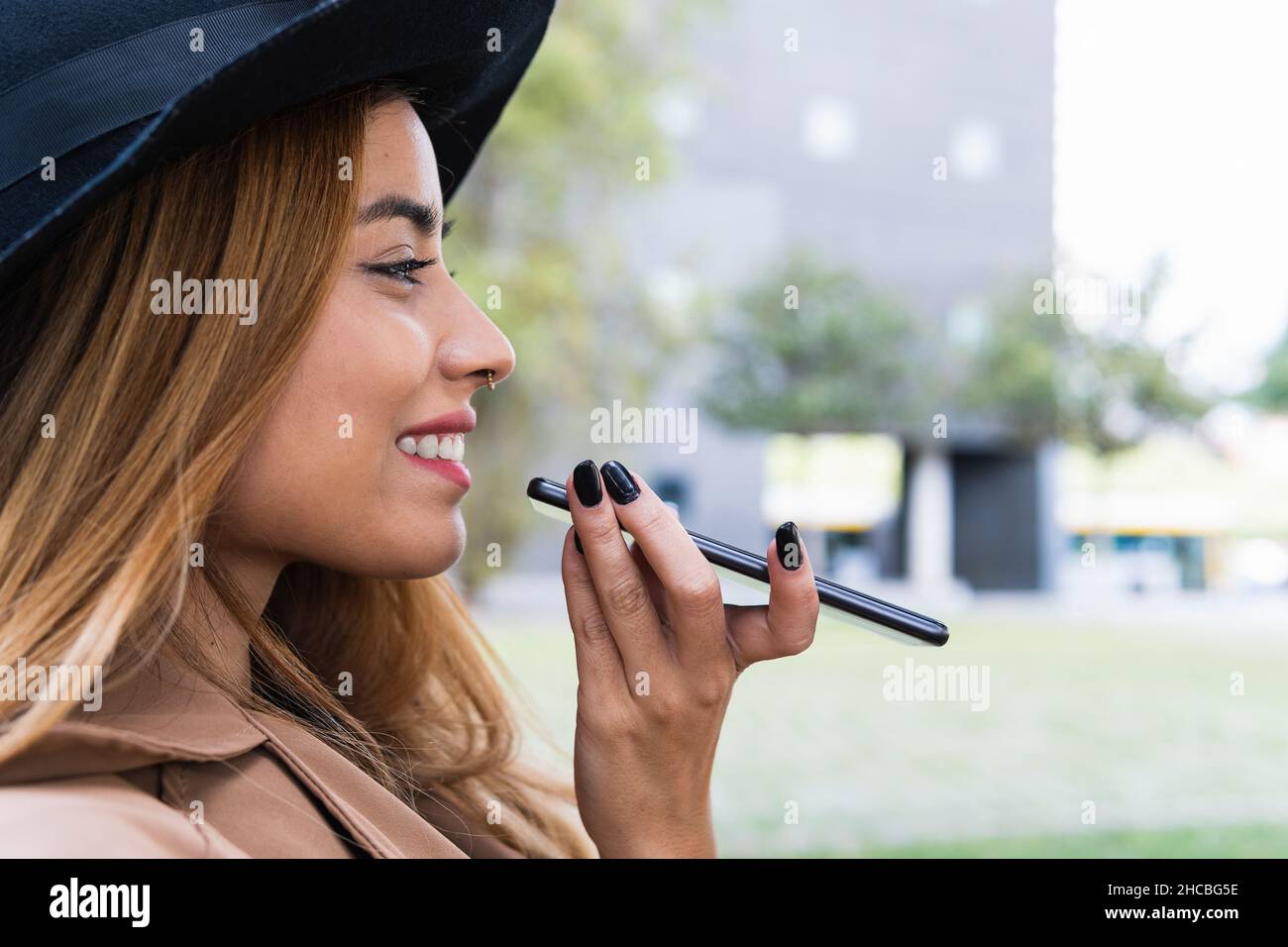 Donna che indossa un cappello che invia la segreteria telefonica tramite smartphone Foto Stock