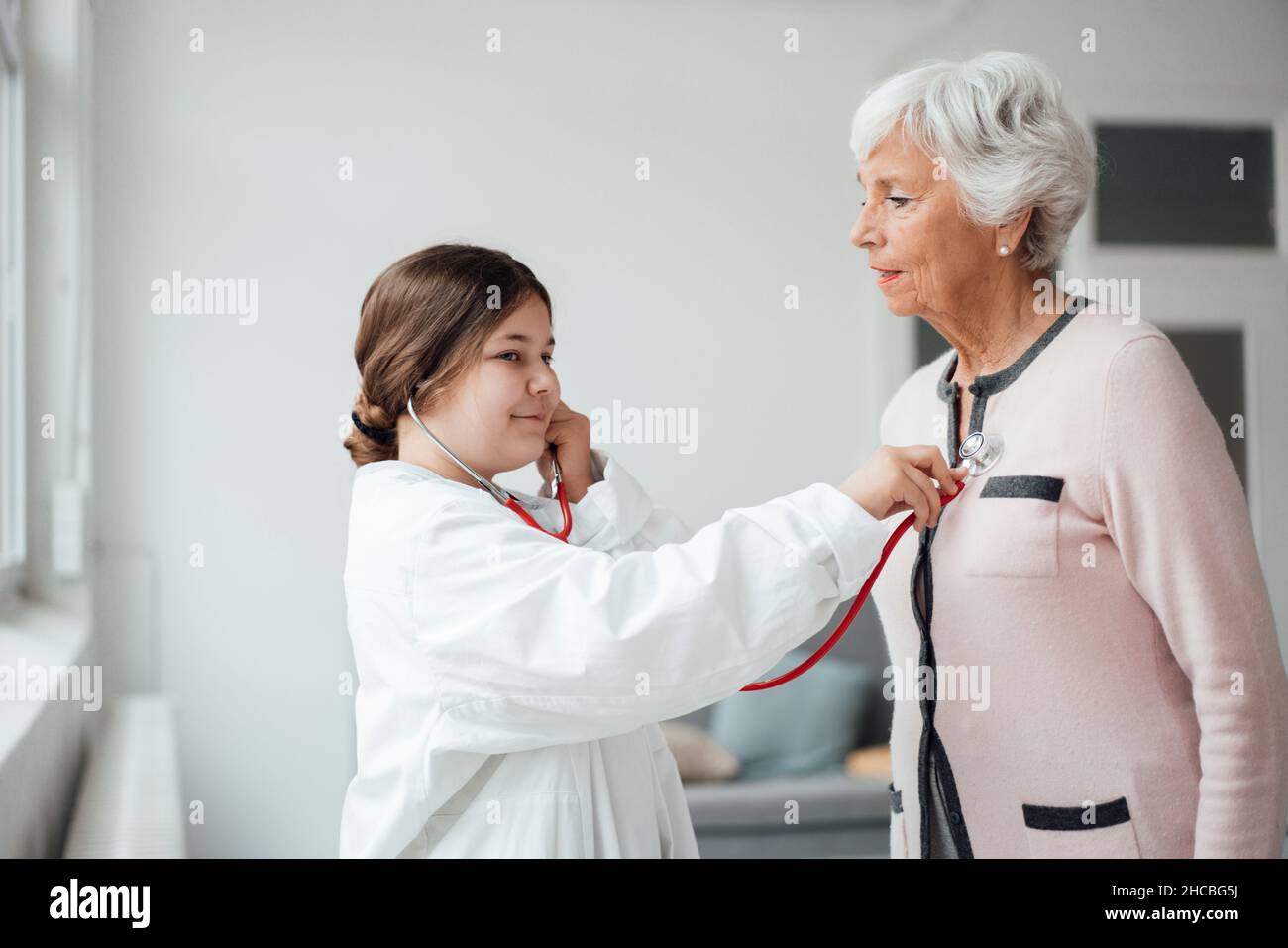 Ragazza giocosa che controlla la donna con martello reflex a casa Foto Stock