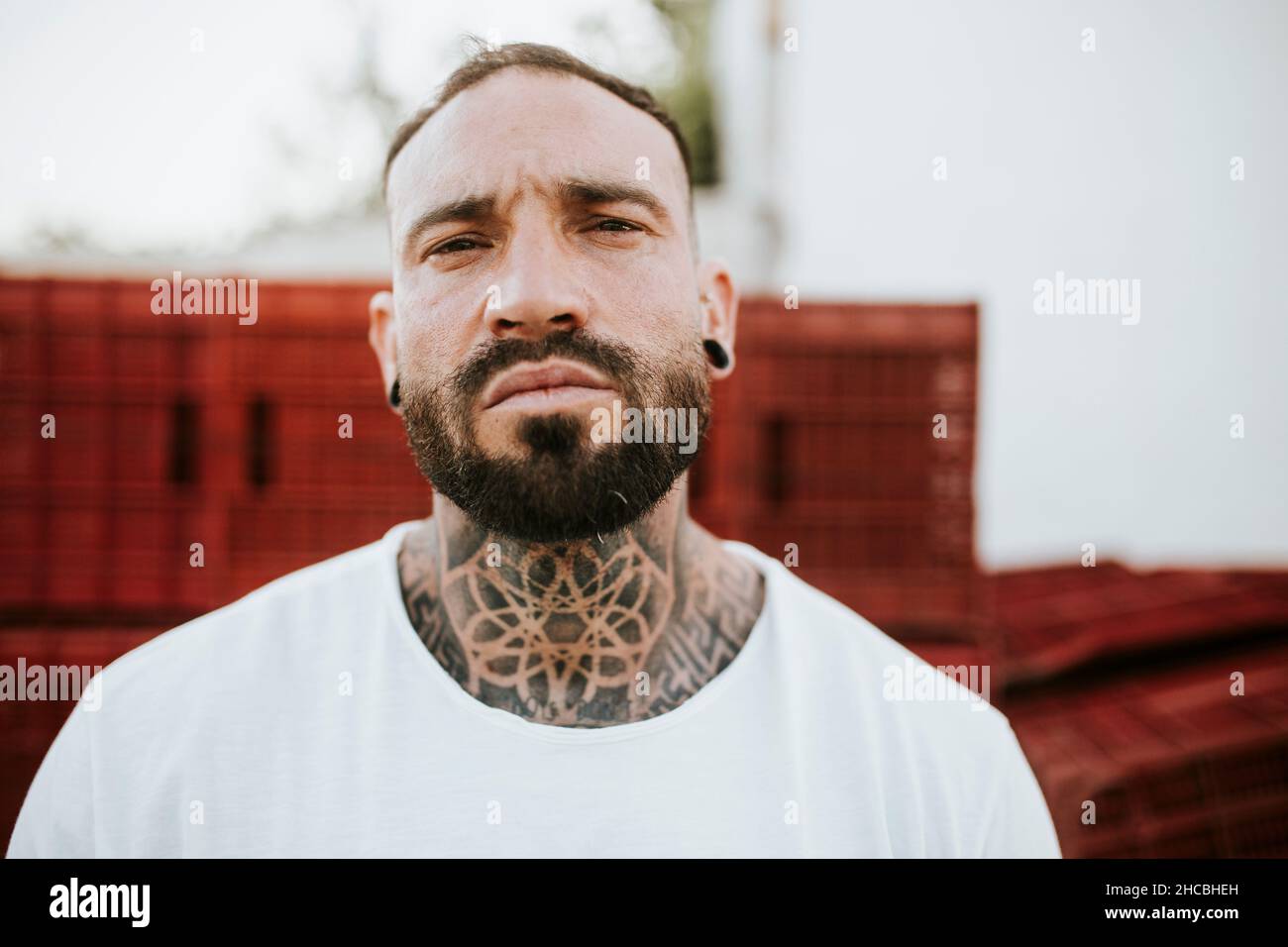 Uomo porticato con tatuaggio sul collo e orecchie trafite Foto stock - Alamy