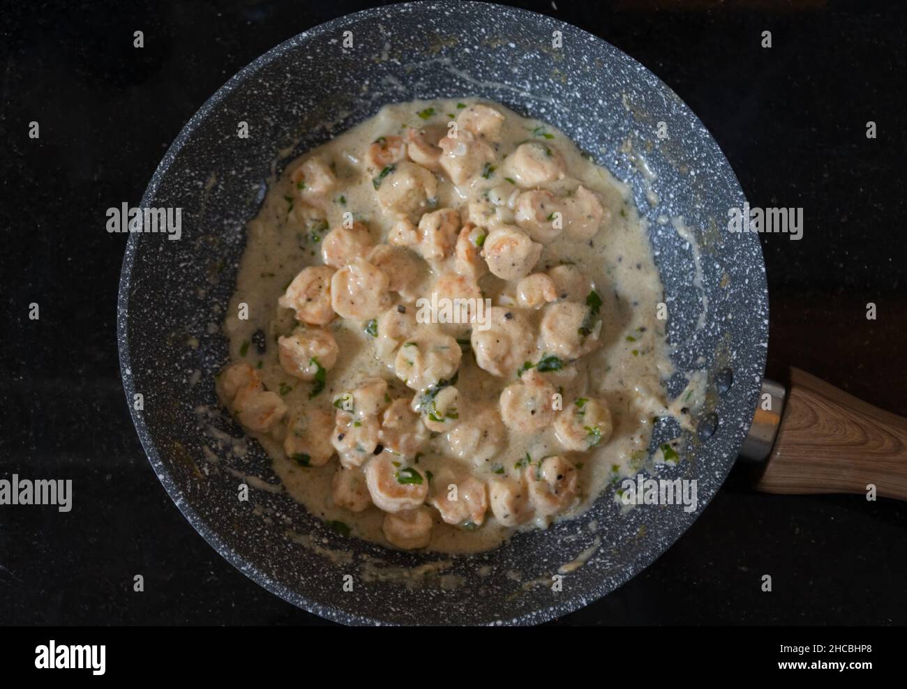Gamberi all'aglio al burro cotti in una padella e presentati su un piano in marmo nero lucido. Gamberi cotti al burro e salsa all'aglio. Foto Stock