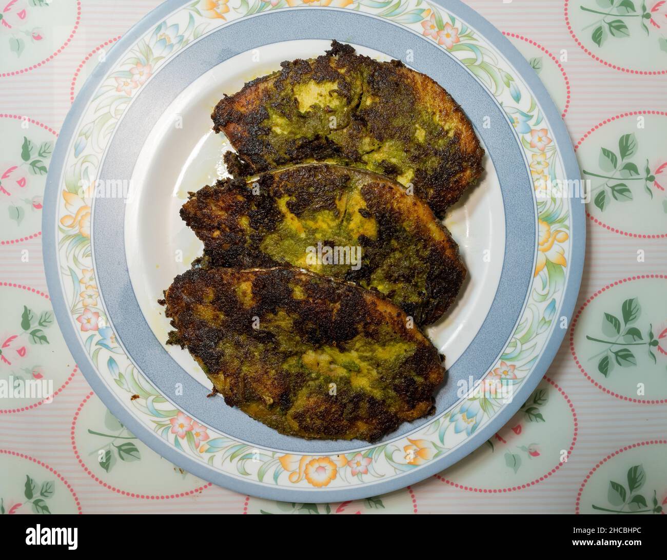 Tre fette fatte in casa di Kingfish fritto alla perfezione in una pasta verde fatta di foglie di Corriander, erbe e spezie. Foto Stock