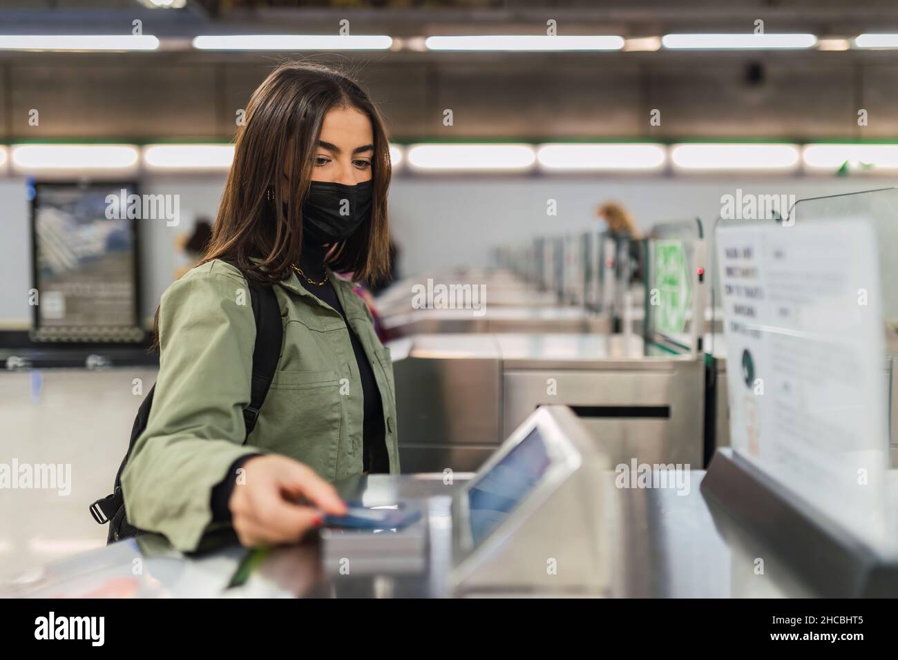 Donna con maschera a pagamento alla barriera di sicurezza in metropolitana Foto Stock