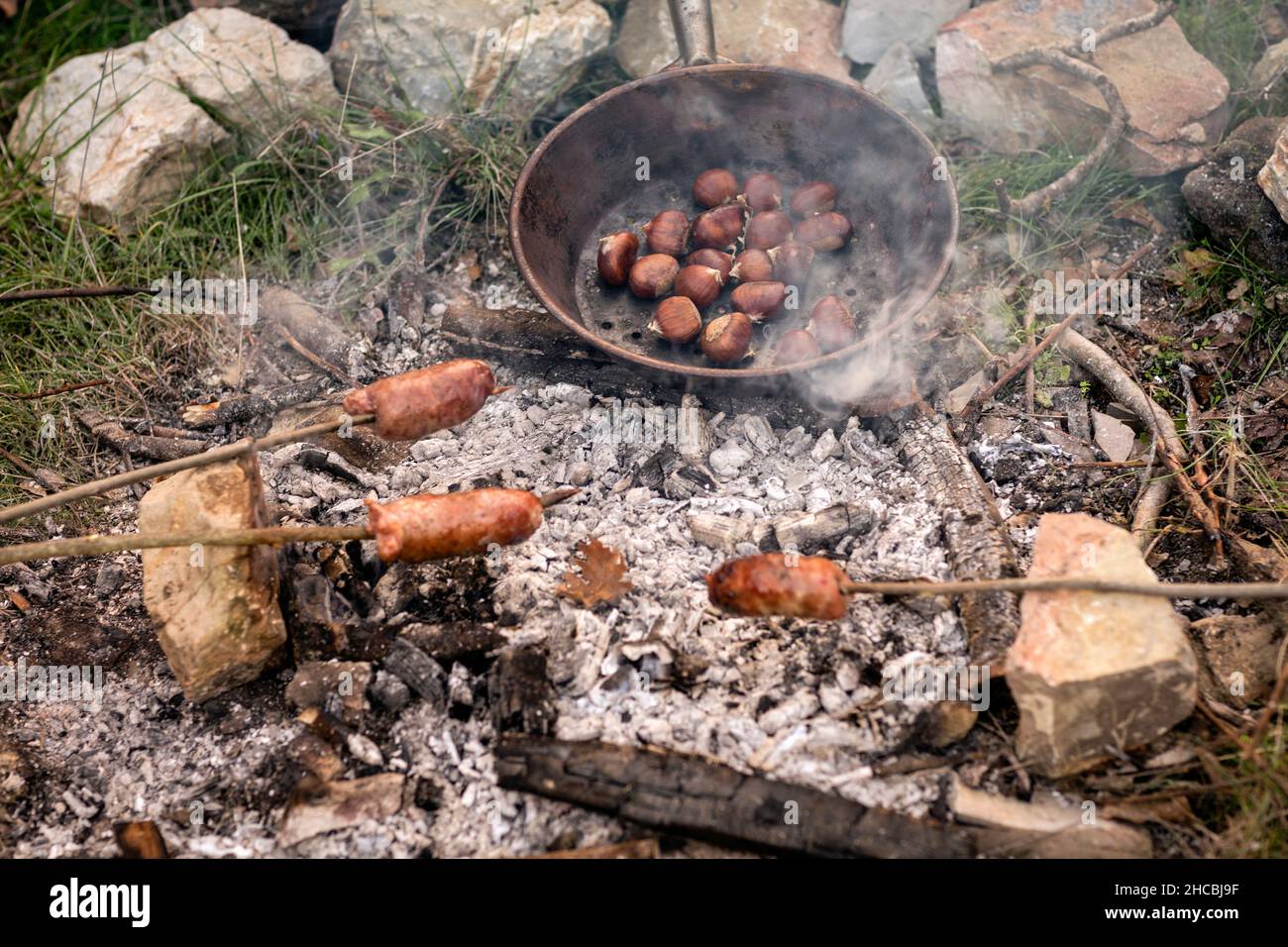 Salsicce e castagne cucinate al fuoco nel bosco Foto Stock