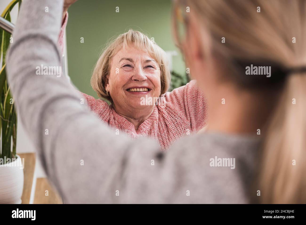 Donna sorridente che dà cinque alti per l'infermiera a casa Foto Stock