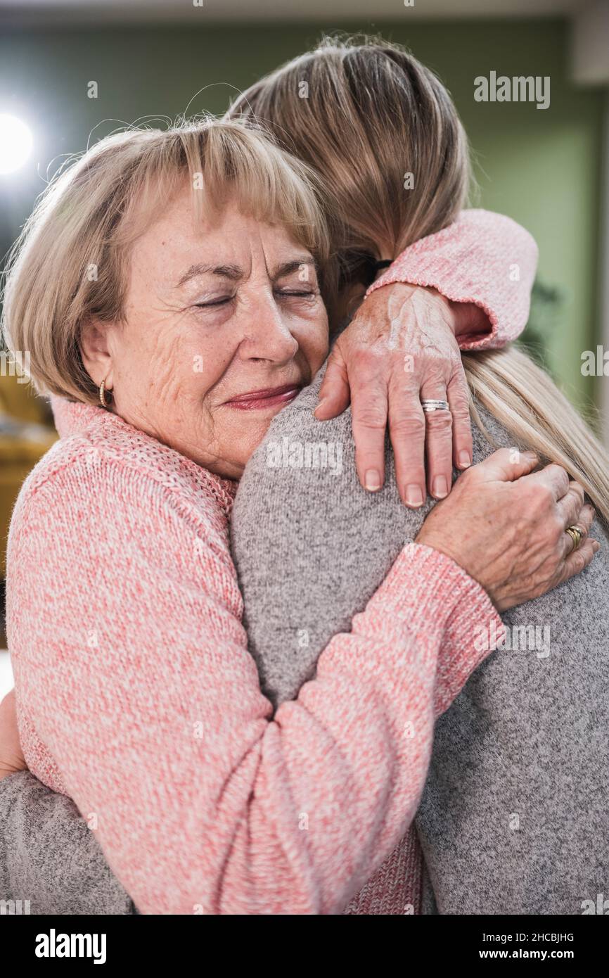 Donna anziana che abbraccia l'infermiera a casa Foto Stock