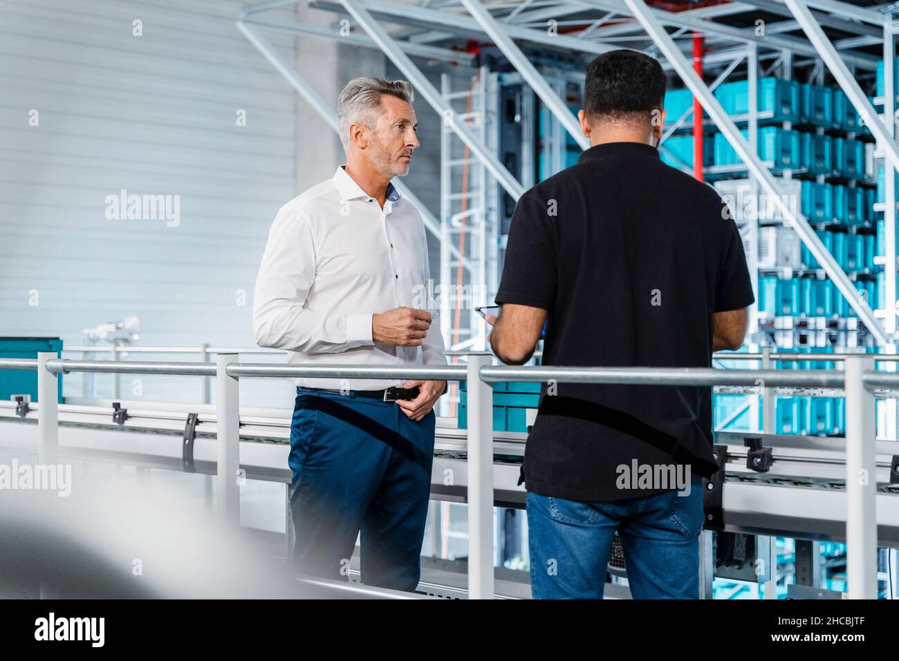 Uomo d'affari che ispeziona il magazzino con il responsabile alla ringhiera Foto Stock