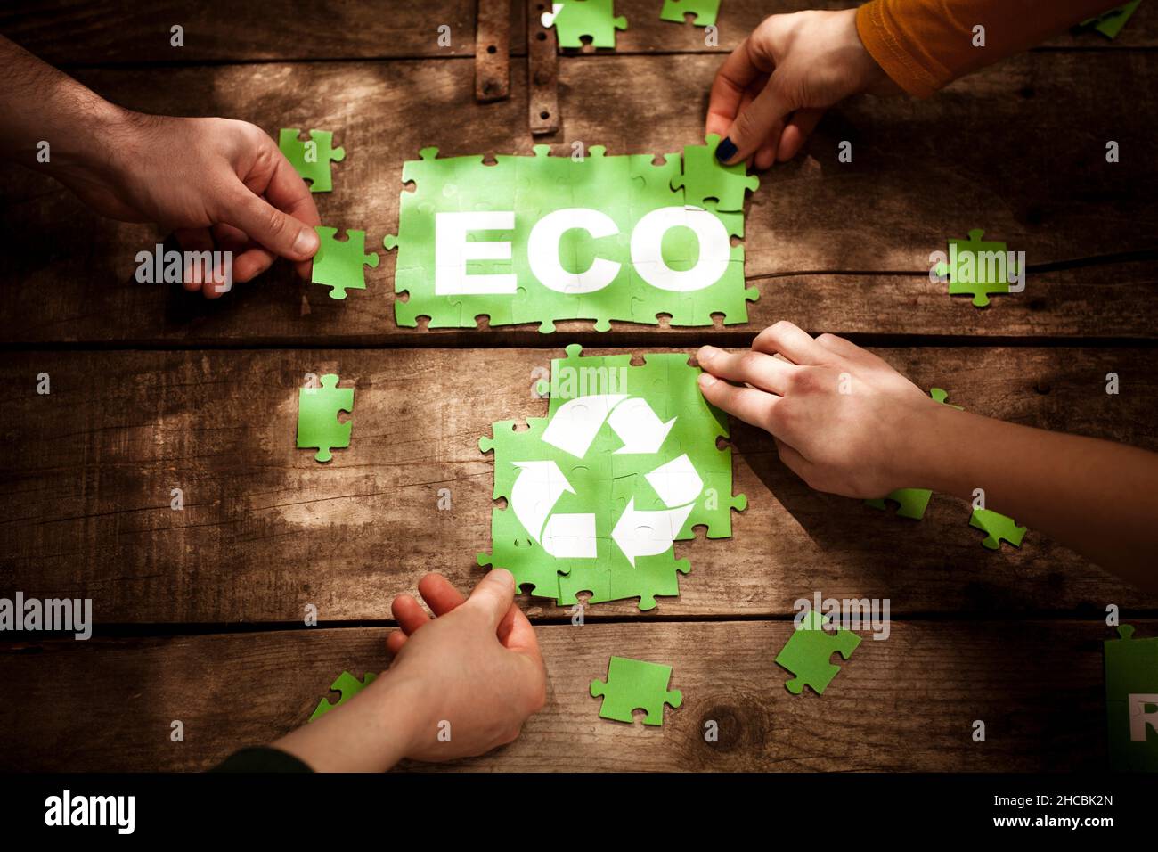 Amici che aderiscono a ECO word e simbolo di riciclaggio sul tavolo Foto Stock