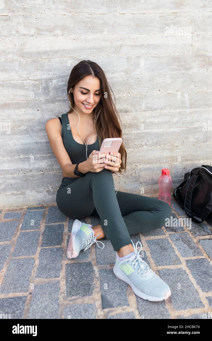 Sorridente sportivo utilizzando il telefono cellulare sul sentiero Foto Stock