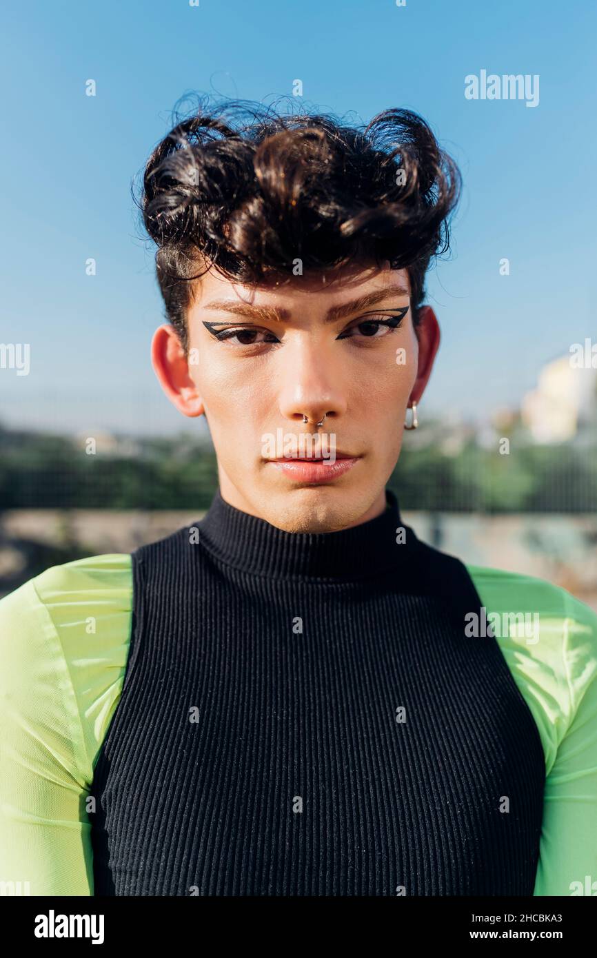 Elegante giovane uomo bello con un taglio di capelli corti in una moda nero  giacca invernale sorge sulla strada Foto stock - Alamy