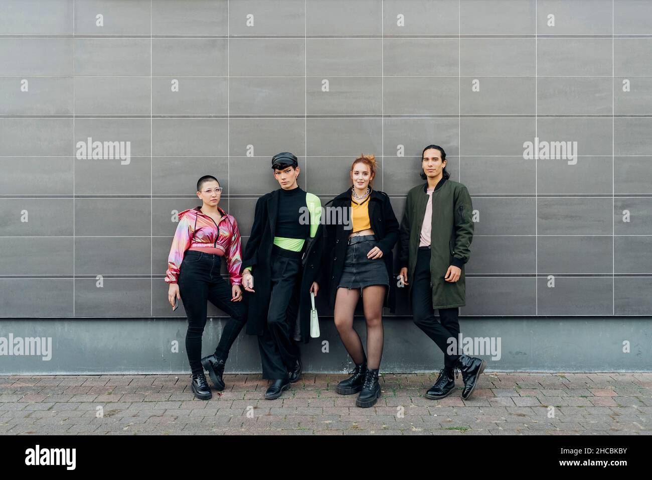 Amici in piedi fianco a fianco di fronte al muro Foto Stock