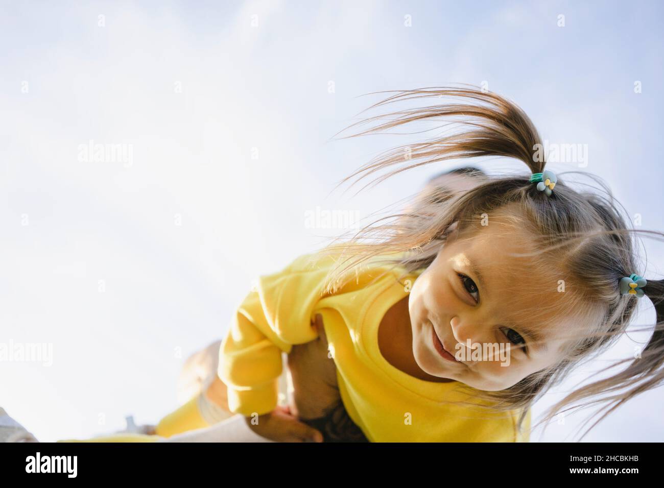 Ragazza sorridente in pigtail giocando con il padre il giorno di sole Foto Stock