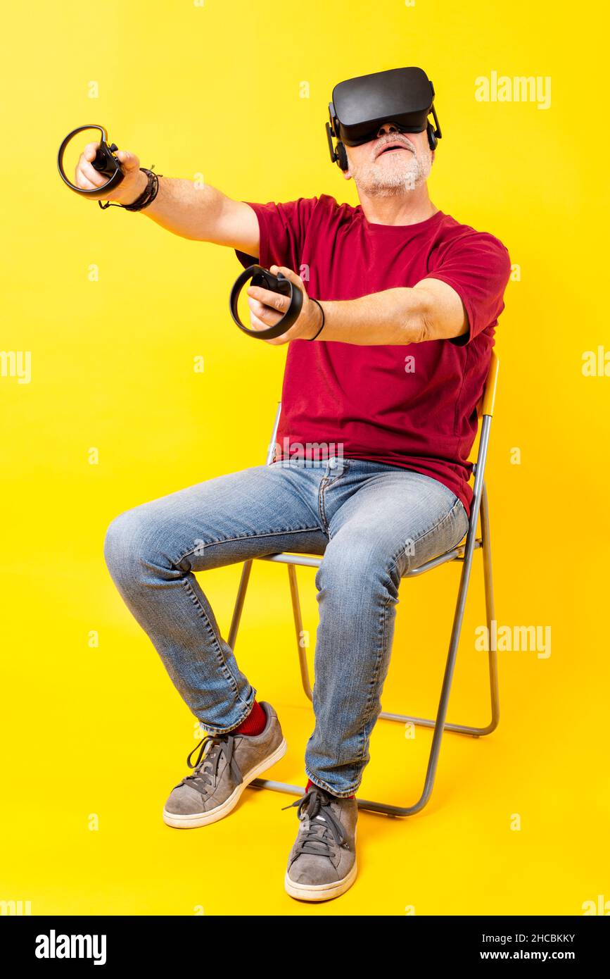 Uomo che indossa una cuffia virtuale utilizzando il controller su sfondo giallo Foto Stock