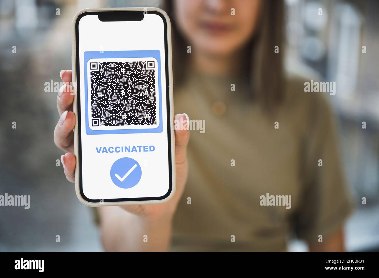 Donna con codice QR vaccinato con segno di spunta sullo schermo mobile Foto Stock