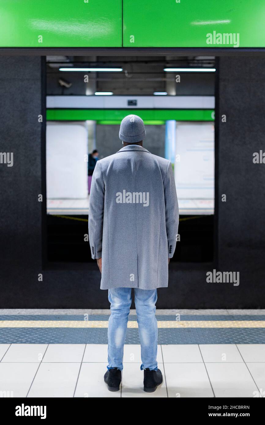 Uomo d'affari con mano in tasca indossare maschera protettiva viso in piedi alla stazione ferroviaria Foto Stock