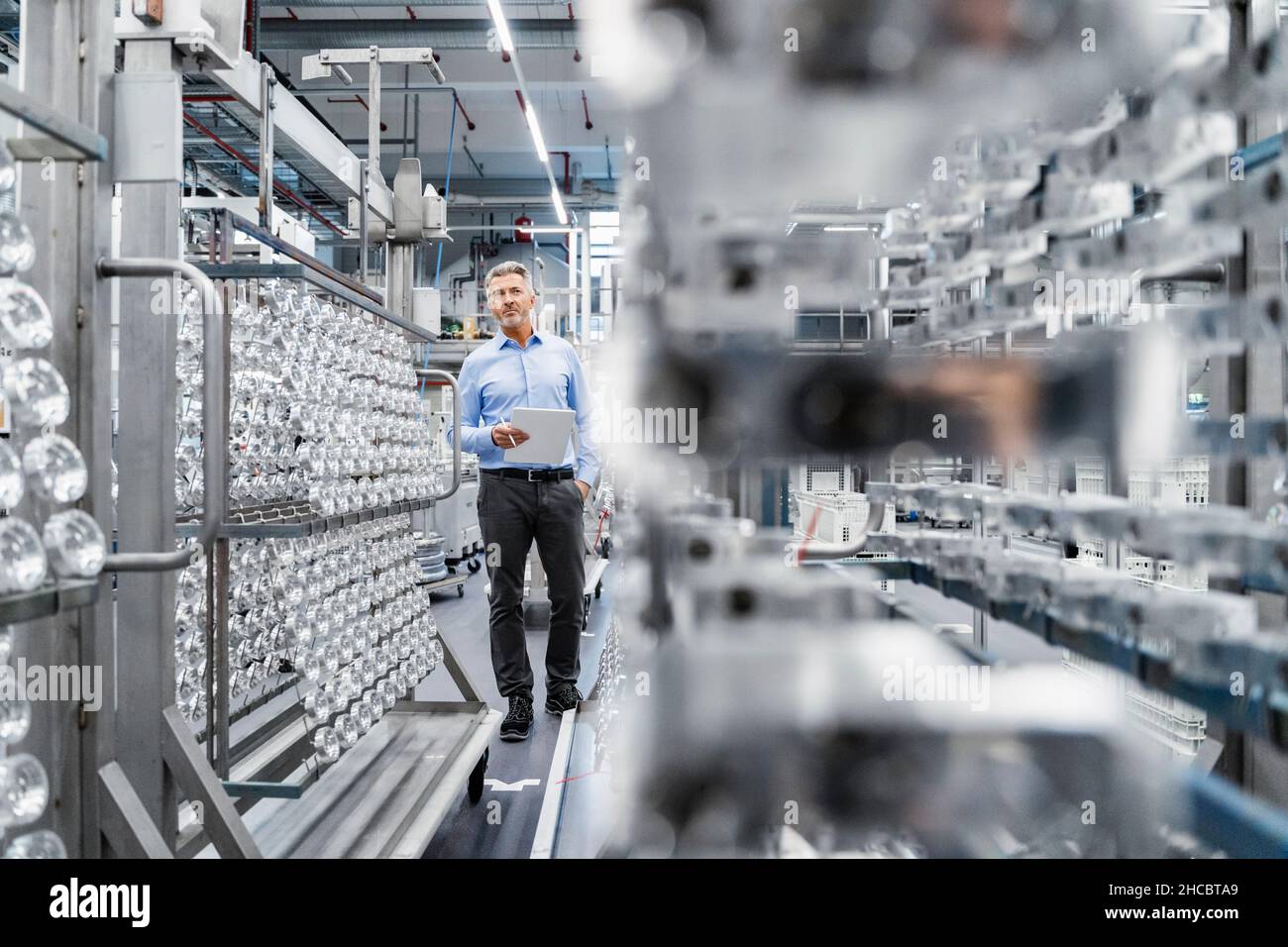 Uomo d'affari che controlla la linea di produzione nell'industria automatizzata Foto Stock