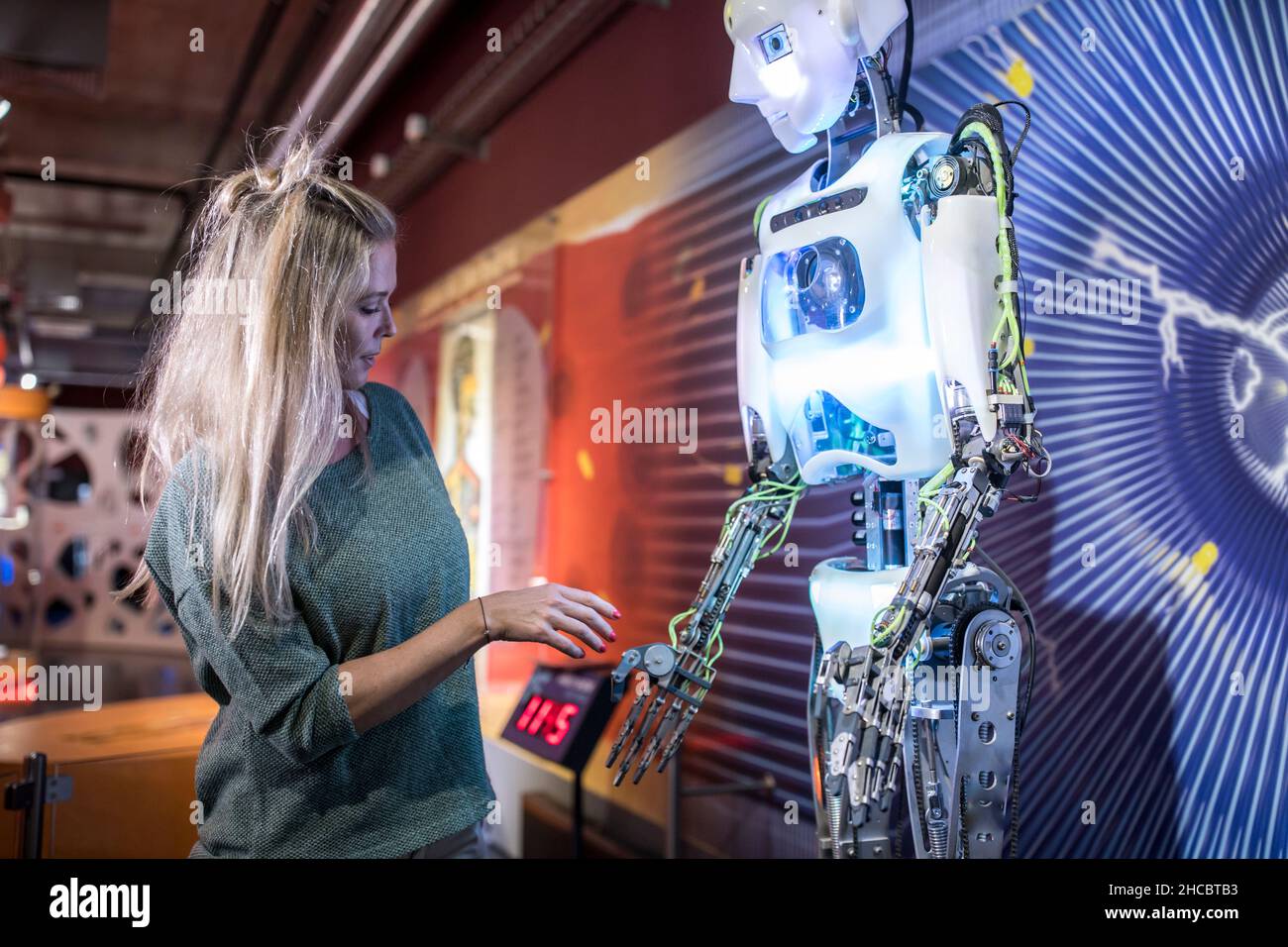 Tecnico che fa handshake con robot umano in officina Foto Stock