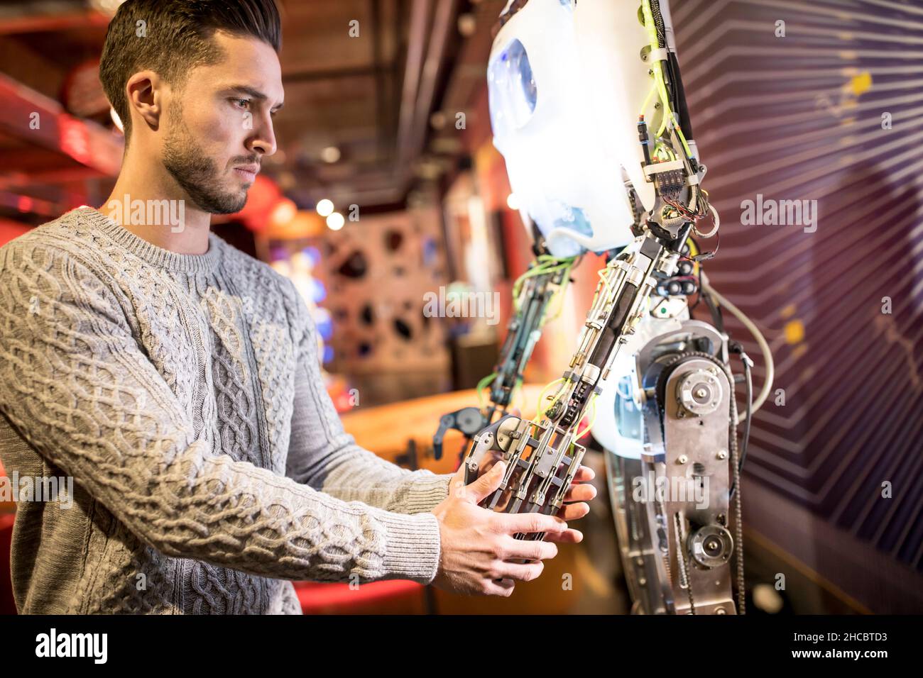 Ingegnere che fa handshake con robot umano in officina Foto Stock