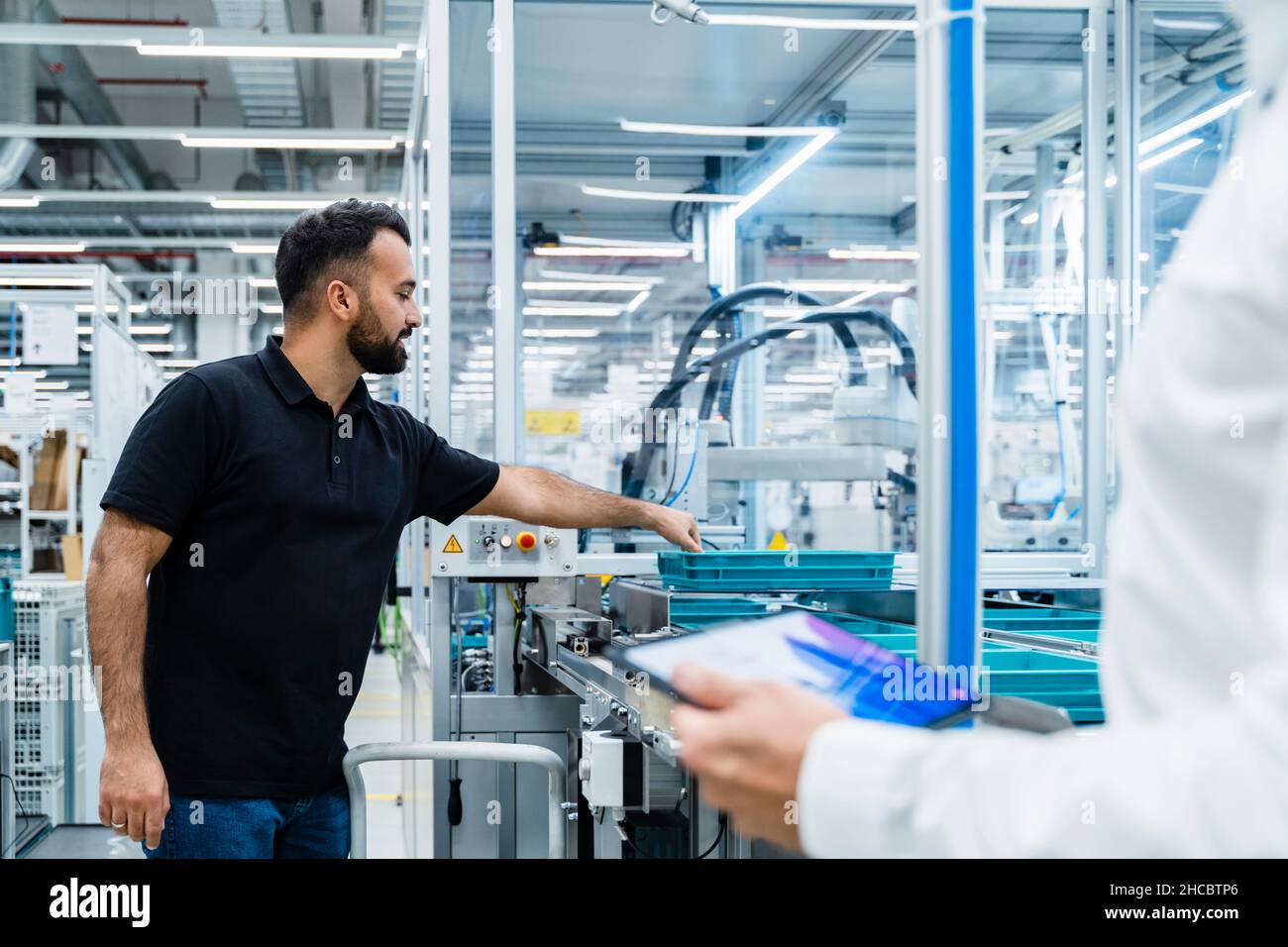 Uomo d'affari che spiega ai tecnici addetti alla manutenzione la linea di produzione della fabbrica Foto Stock