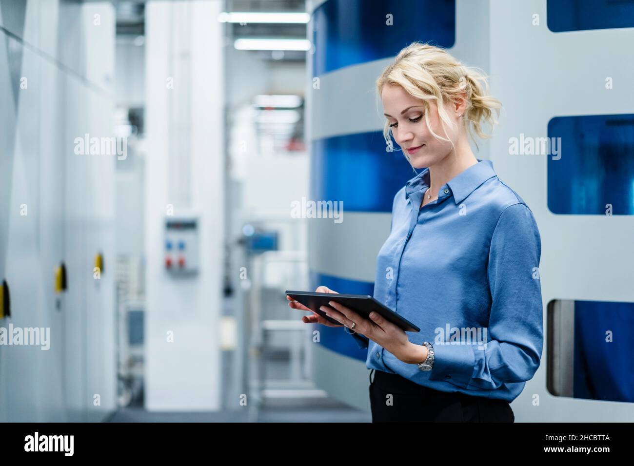 Donna d'affari che utilizza un tablet PC nell'industria elettrica Foto Stock