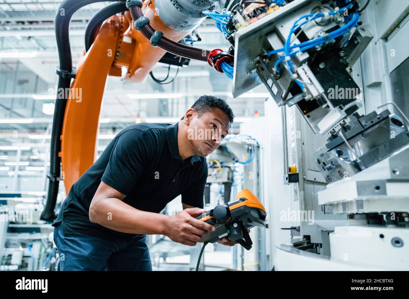 Ingegnere che opera il braccio robotico nell'industria elettrica Foto Stock