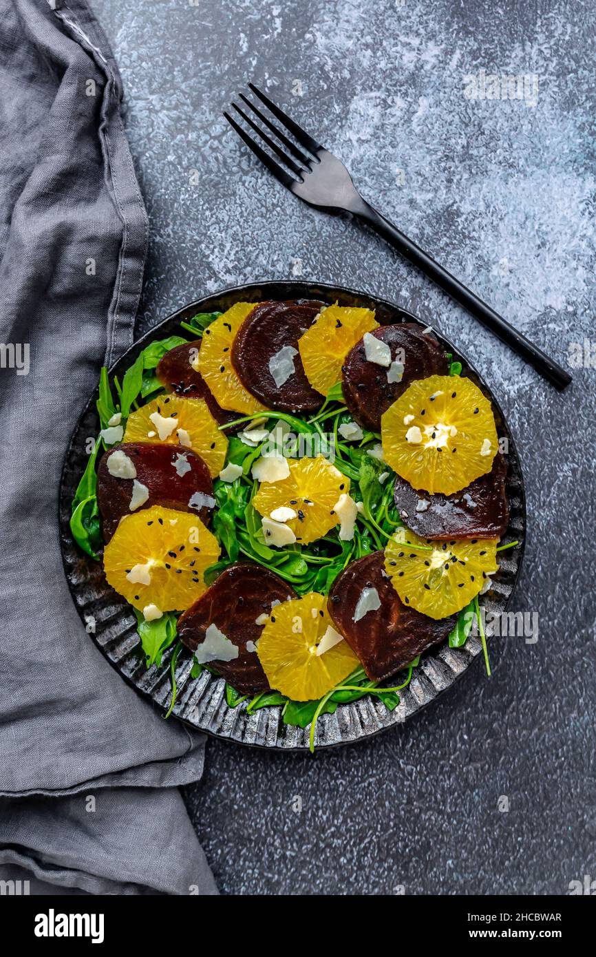 Studio di piatto di carpaccio vegetariano con fette di arance e barbabietole, rucola, parmigiano e semi di sesamo nero Foto Stock