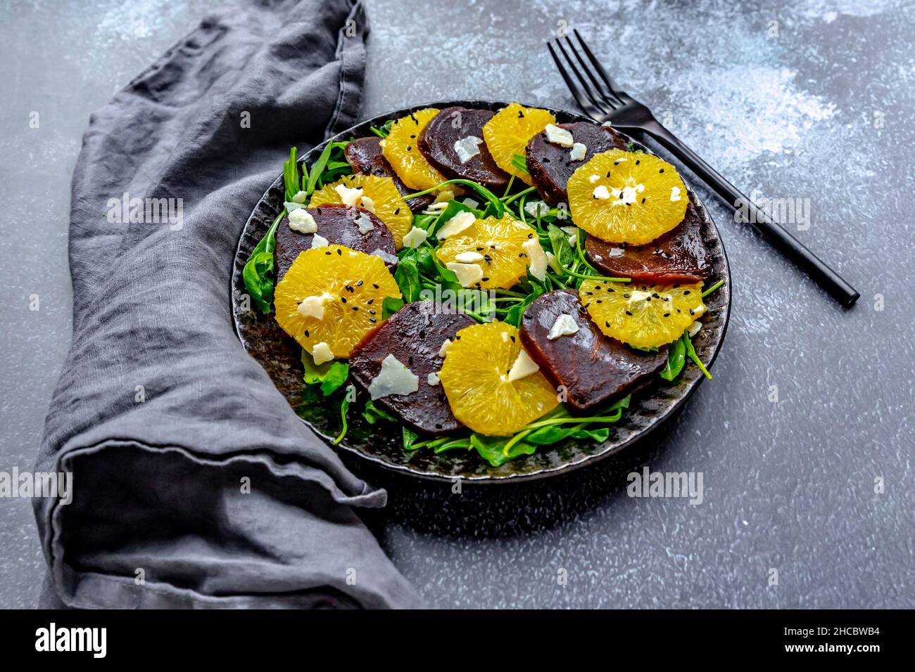 Studio di piatto di carpaccio vegetariano con fette di arance e barbabietole, rucola, parmigiano e semi di sesamo nero Foto Stock