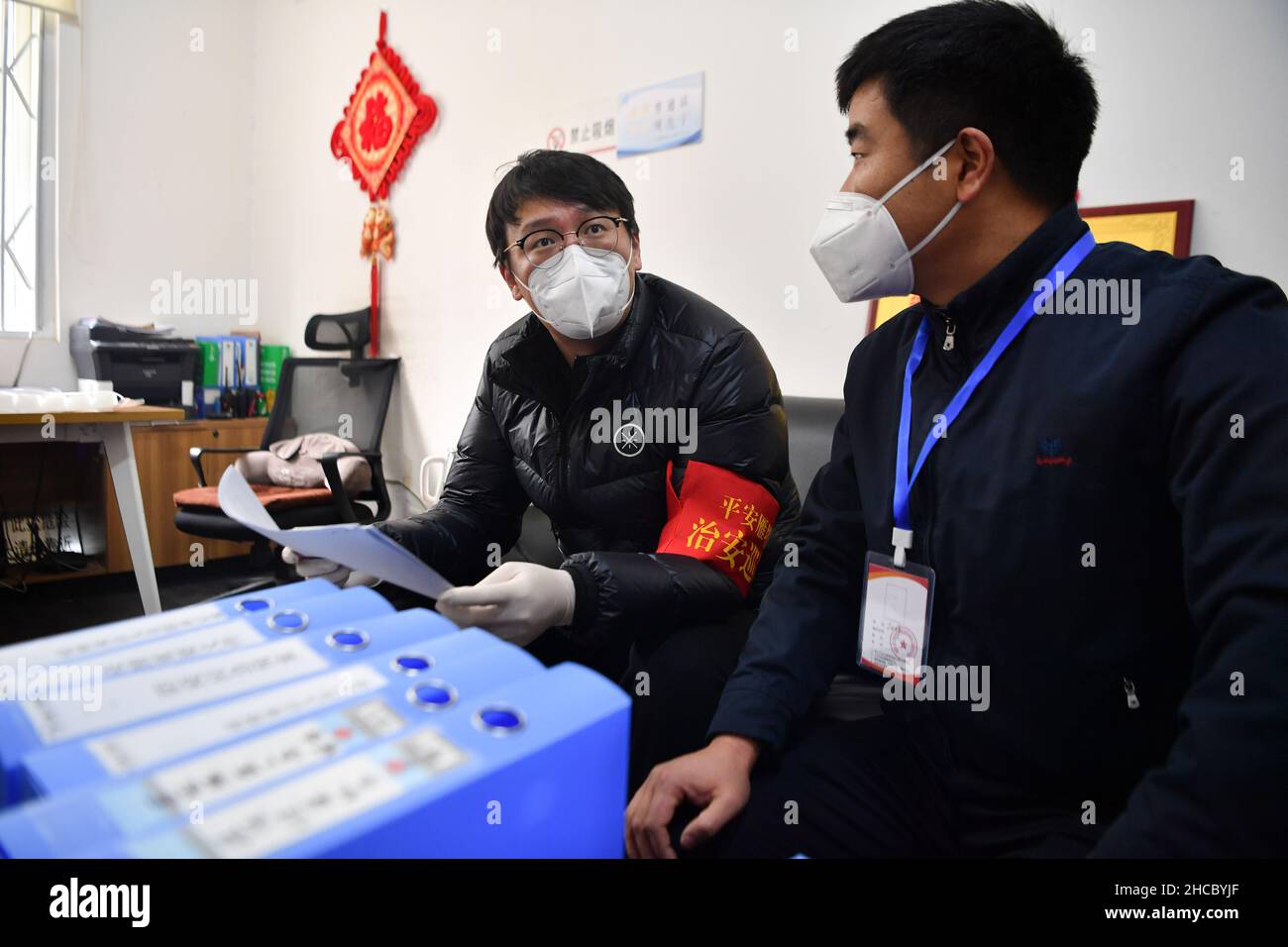 XI'an, la provincia cinese di Shaanxi. 27th Dic 2021. L'operaio governativo Lu Chenyang (L) controlla i file sulla prevenzione e il controllo delle epidemie nel distretto di Yanta di Xi'an, provincia Shaanxi della Cina nordoccidentale, 27 dicembre 2021. Decine di migliaia di lavoratori del governo si sono Uniti in prima linea in tutta la città per estordire il coronavirus a Xi'an, capitale della provincia Shaanxi della Cina nord-occidentale. Credit: Zhang Bowen/Xinhua/Alamy Live News Foto Stock