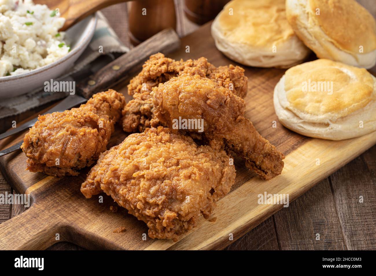 Cena con coscia e coscia di pollo fritto con biscotti e purè di patate su un rustico tavolo in legno Foto Stock