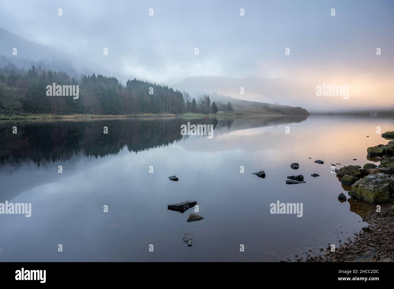 Nebbia con bagliore caldo sul serbatoio Dovestones con riflesso nell'acqua Foto Stock