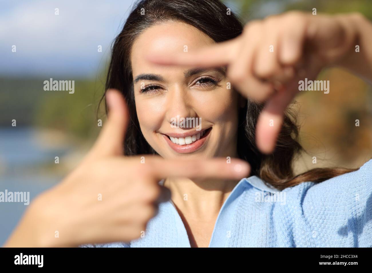 Ritratto della vista frontale di una donna che incornicia con le mani che ti guardano in montagna Foto Stock