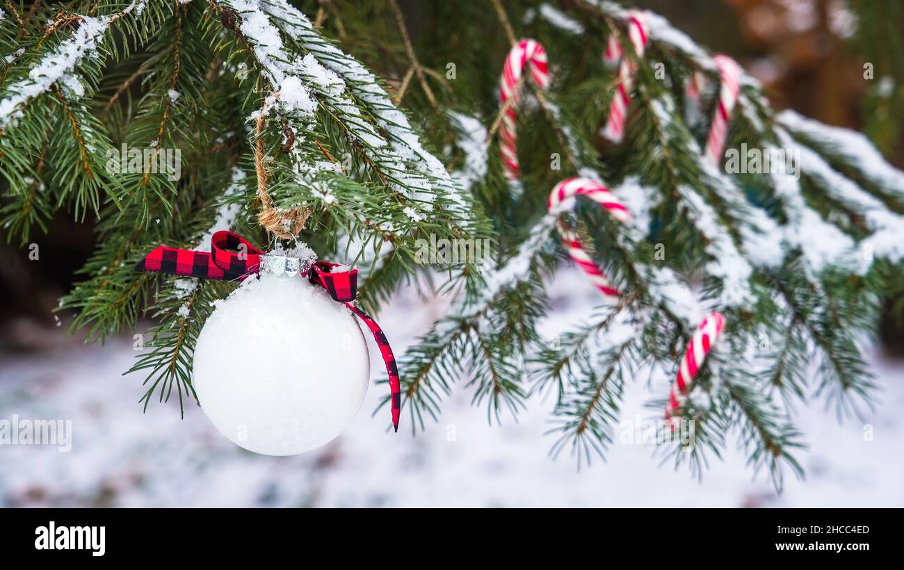 Palla di Natale con decorazione caramella all'aperto su albero con neve Foto Stock
