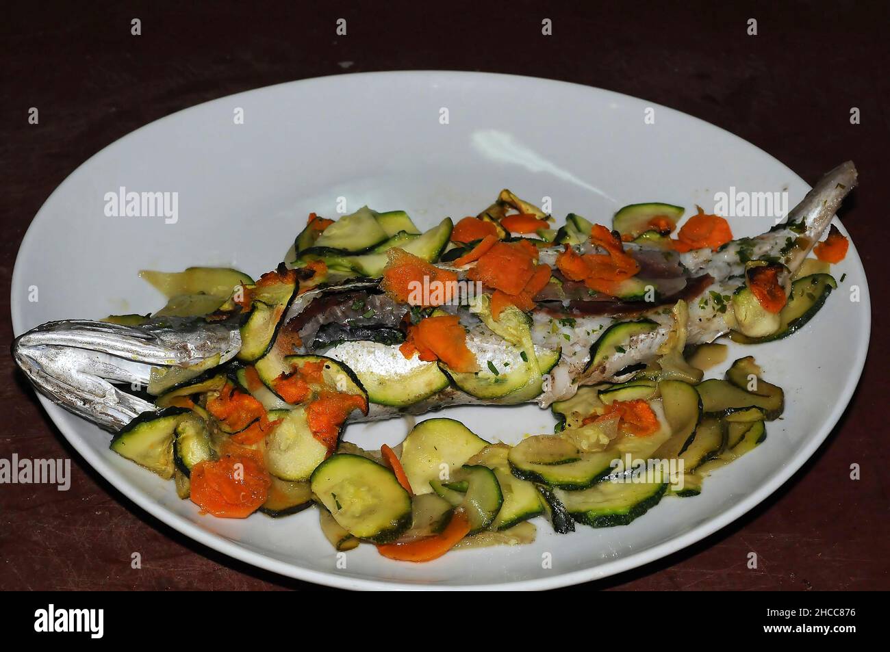 filetto di branzino al forno sul grill in piatto bianco Foto Stock