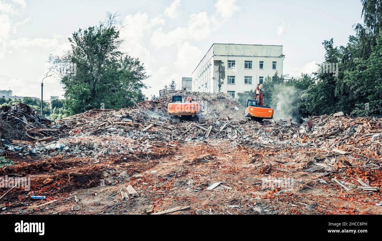 Gli escavatori demoliscono l'edificio. Smontaggio della costruzione Foto Stock