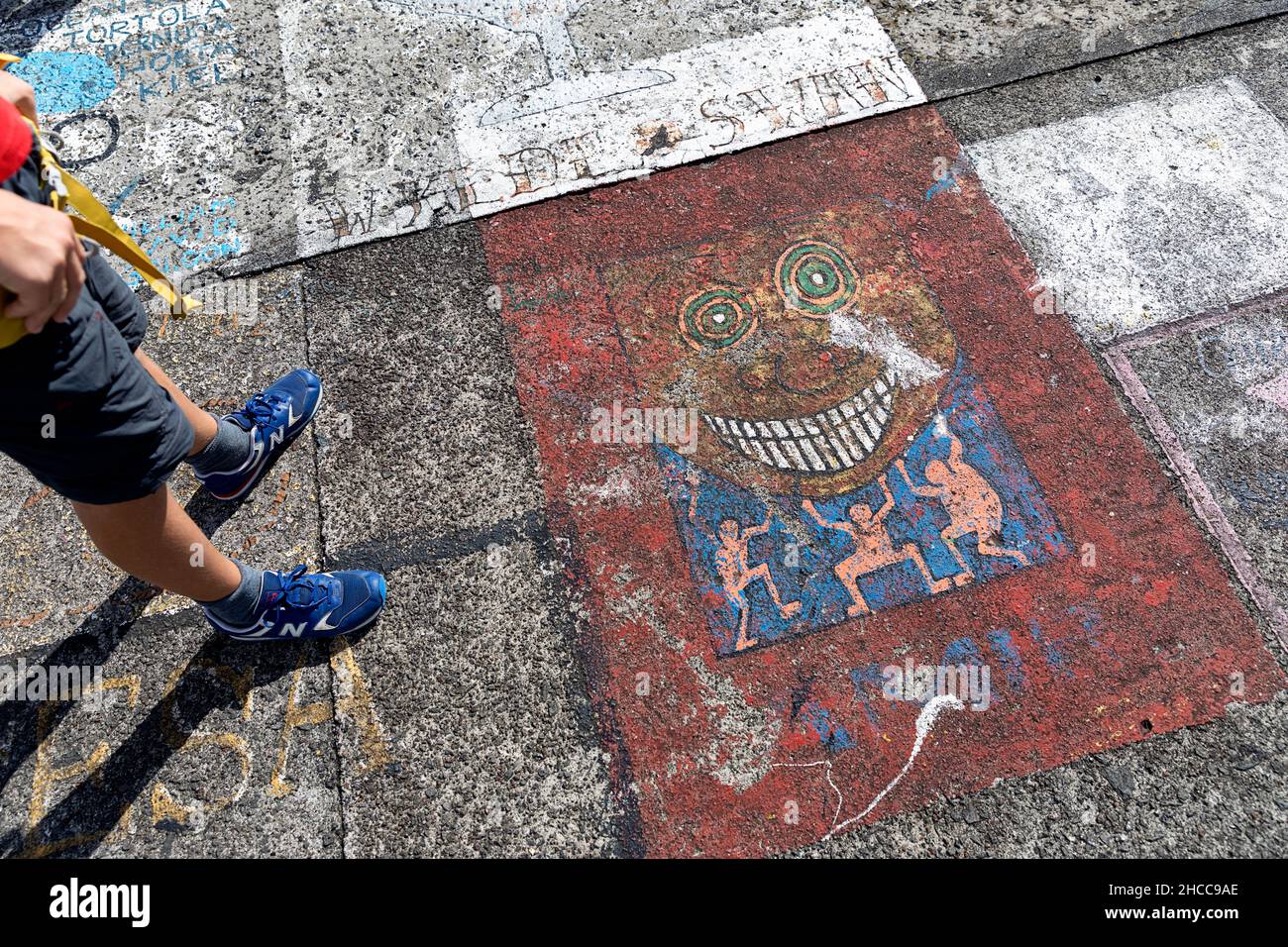 Ragazzo in piedi da muro di molo dipinto marinaio, mostra all'aperto di dipinti di marinai, Horta, Isola di Faial, Azzorre, Portogallo Foto Stock
