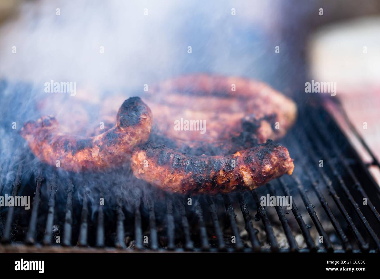 Grigliare le salsicce sulla griglia per barbecue. Deliziose salsicce sulla griglia al carbone Foto Stock