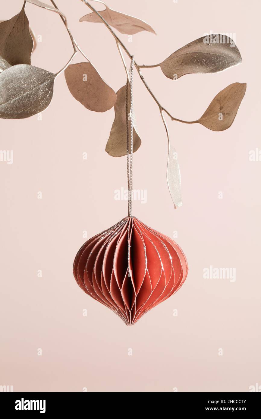 Decorazioni natalizie in carta a nido d'ape su ramo dorato su sfondo beige. Vacanze stagionali, biglietto d'auguri, vacanza ecologica. Foto Stock