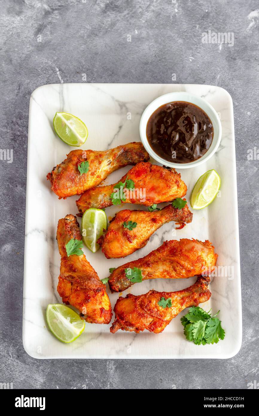 Bacchette di pollo al forno su un piatto bianco con condimento Top Down foto Foto Stock
