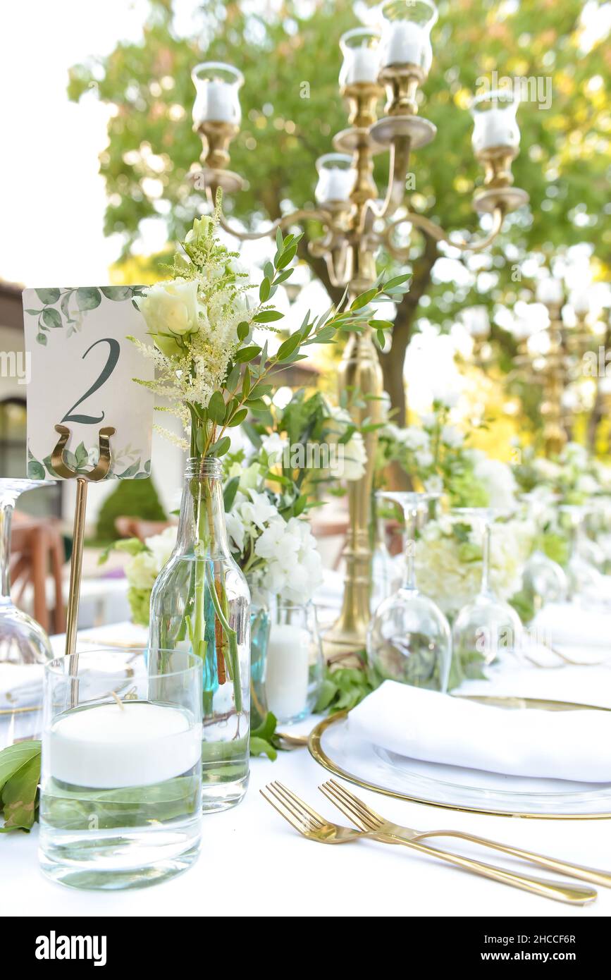 Una foto verticale di tavoli decorati con fiori e candele su una tovaglia bianca e un cartello con la scritta '2' pronto per un evento Foto Stock