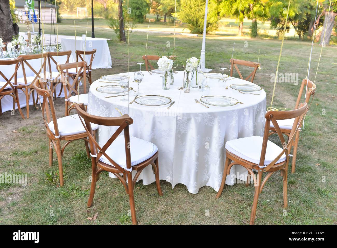 Tavolo rotondo con tovaglia bianca decorata con tavoli e sedie in stile  rustico Foto stock - Alamy