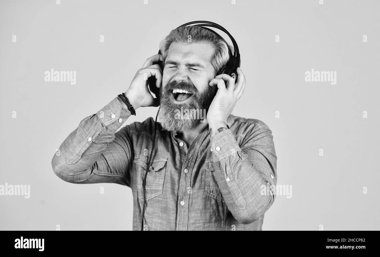 mi piace molto. brutale hipster indossare auricolari, cantare e ballare. Ascoltare la musica preferita. L'uomo ascolta la musica con le cuffie. L'uomo barbuto Foto Stock