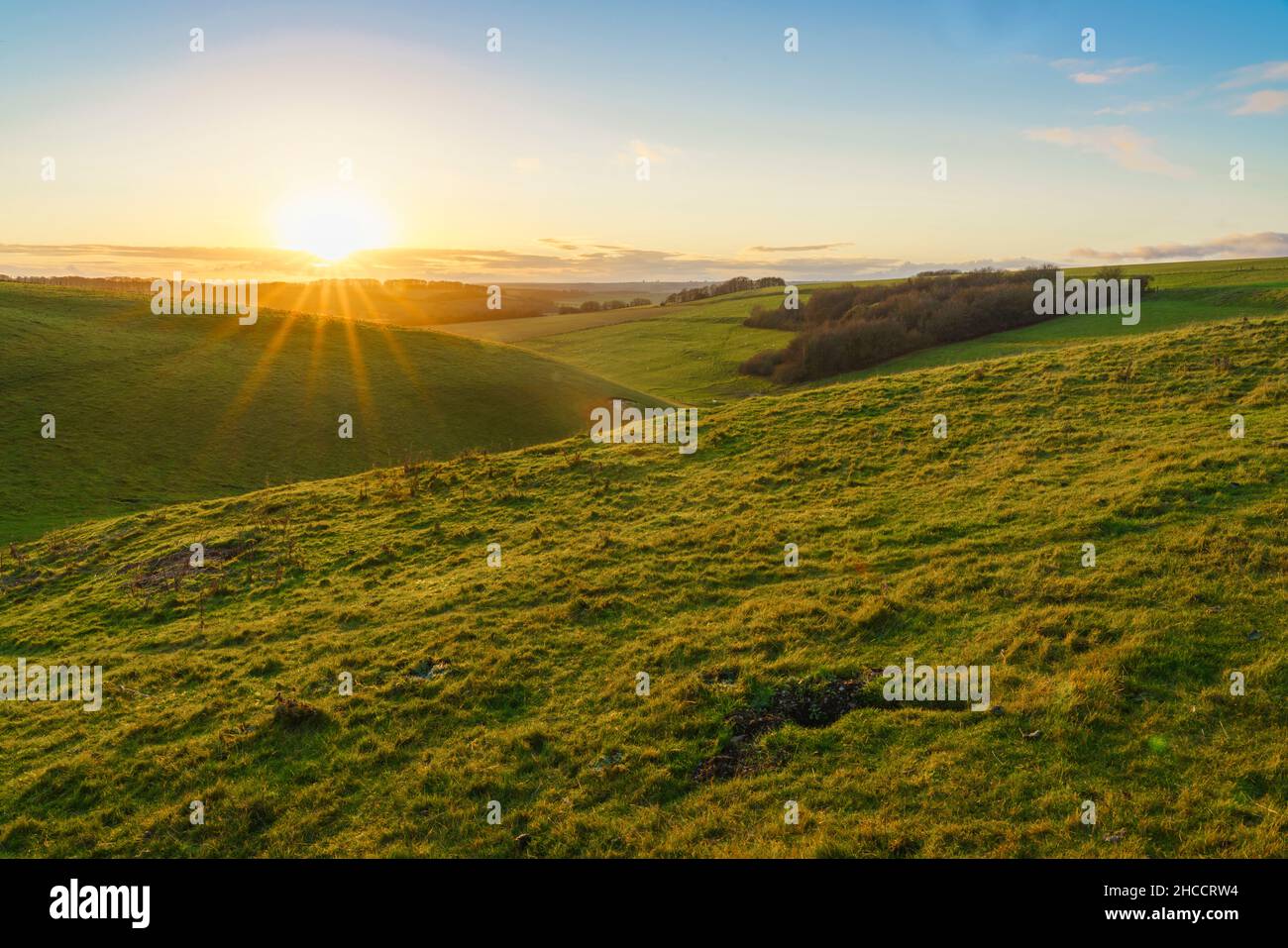 Un tramonto dorato, bassa nuvola illuminata all'orizzonte su una valle verde erba profonda, North Wessex Downs AONB Foto Stock