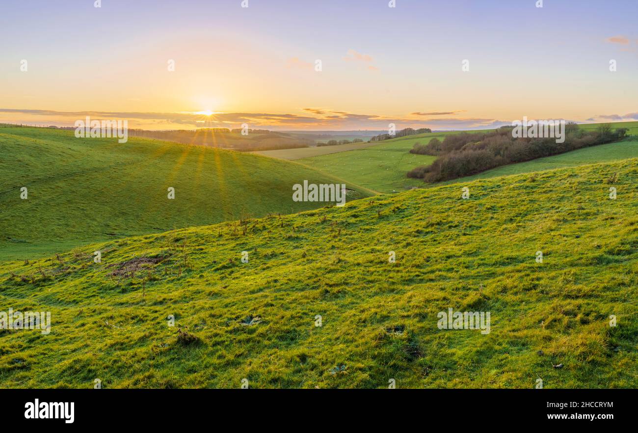 Un tramonto dorato, bassa nuvola illuminata all'orizzonte su una valle verde erba profonda, North Wessex Downs AONB Foto Stock