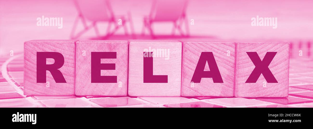 Relax - un'iscrizione su blocchi di legno cubo sulla spiaggia soleggiata beckground con riflessione. Ridurre stress concetto di salute mentale Foto Stock