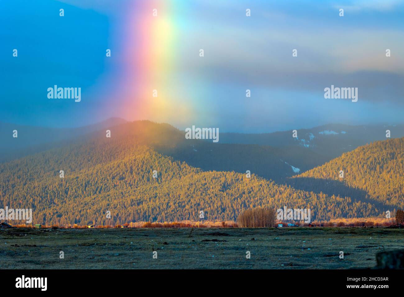 Bellissimo scatto di un arcobaleno sulle colline coperte di verde Foto Stock