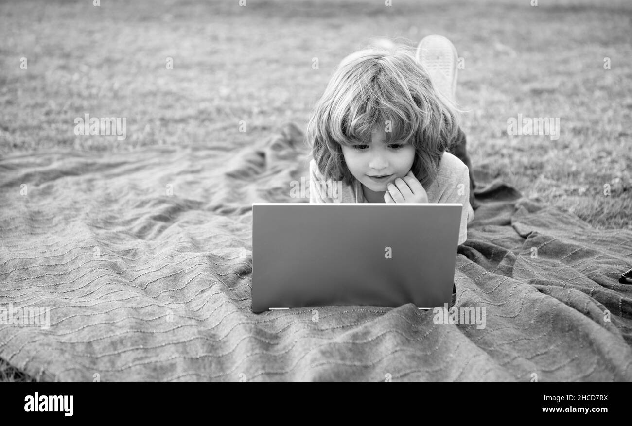 Ragazzo bambino utilizzare laptop computer apprendimento tecnologia rilassante su coperta naturale all'aperto, corsi on-line Foto Stock