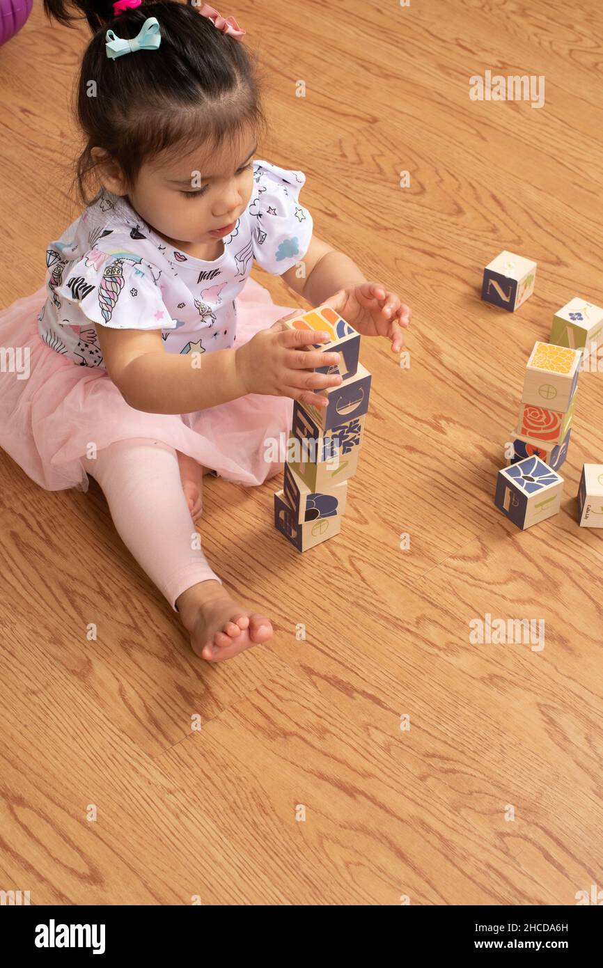 bambina di 17 mesi che fa torre di blocksbare in legno Foto Stock