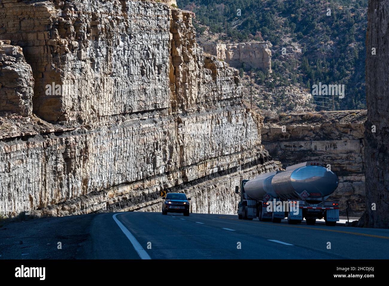 Autocisterna e auto che attraversano una strada tagliata con giacimenti di carbone sull'autostrada 6 a Carbon County, Utah. Foto Stock