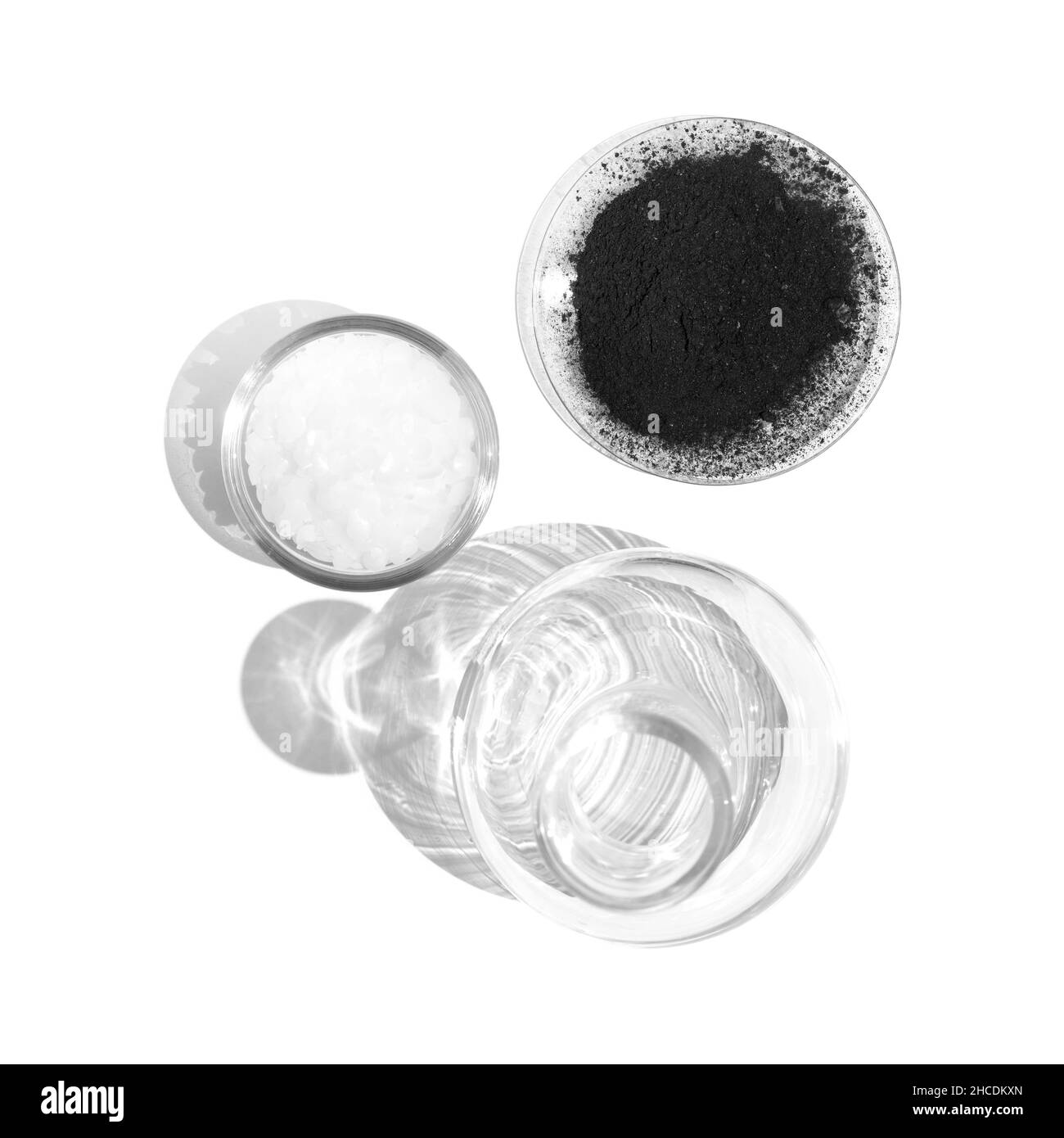 Polvere di carbone in vetro Chemical Watch porre accanto alla cera di cetilesteri in un contenitore di vetro e un matraccio di Erlenmeyer sul tavolo da laboratorio. Vista dall'alto Foto Stock